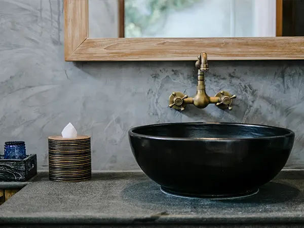 Black vessel sink with golden faucet