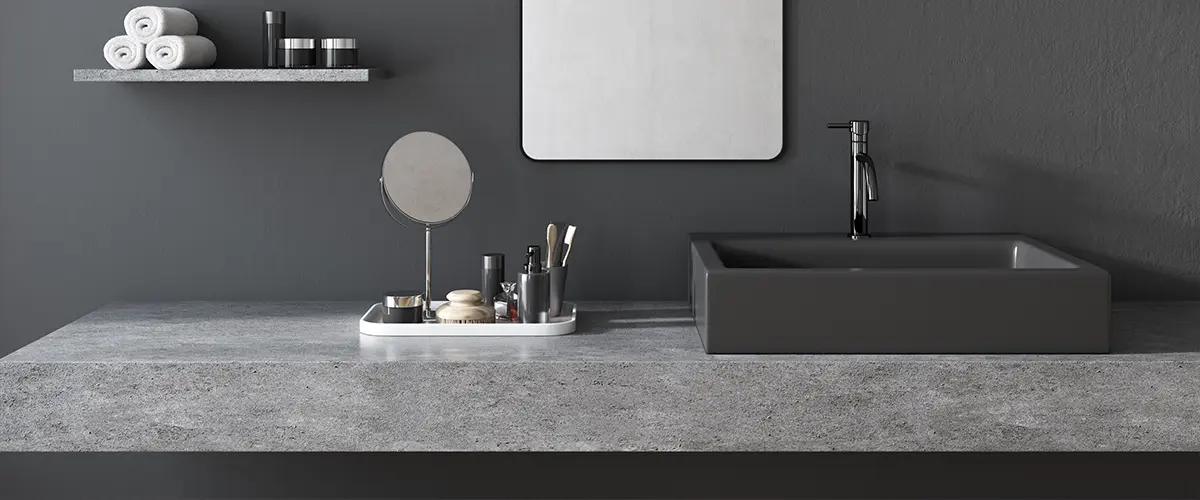 A concrete countertop in a dark gray bathroom
