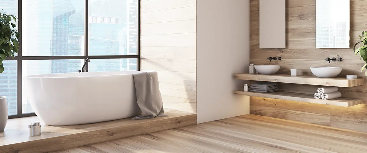 A bathroom with wood floor, freestanding tub in front of a large window, and a simple vanity