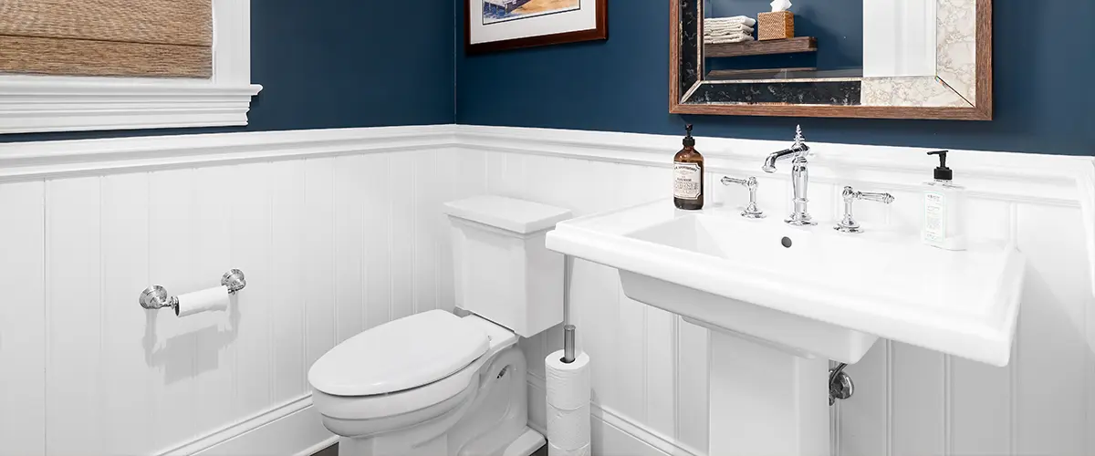 A sink and toilet in a bath with navy blue walls