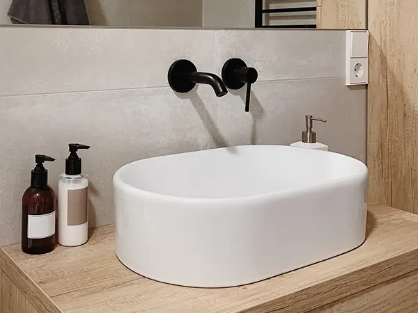 A beautiful vessel sink with dark fixtures