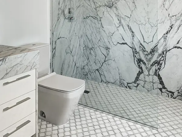 A toilet in a bathroom with marble walls