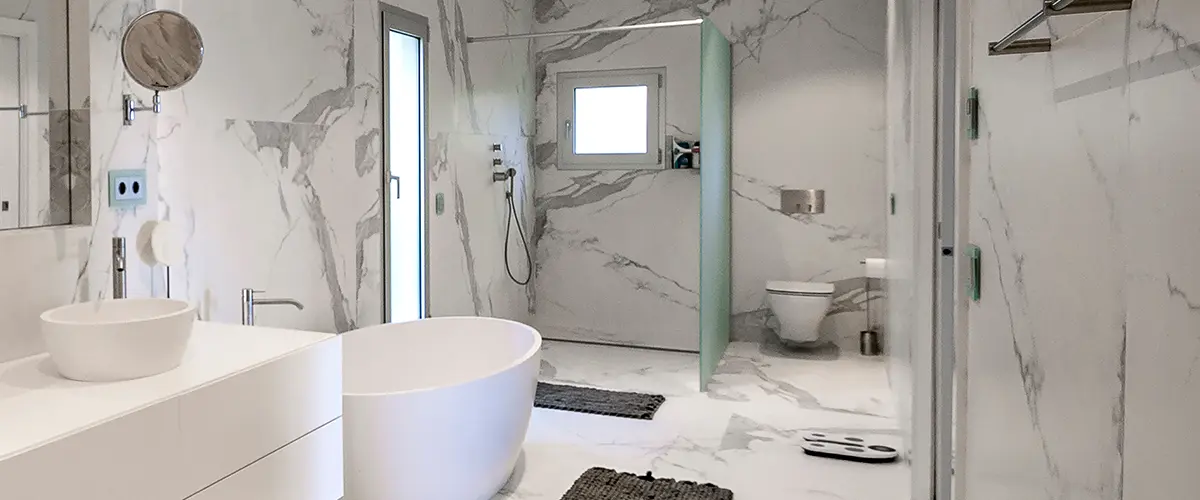 A glass walk-in shower with a freestanding tub