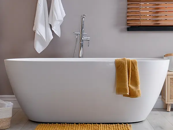 A tub with a yellow mat and towel