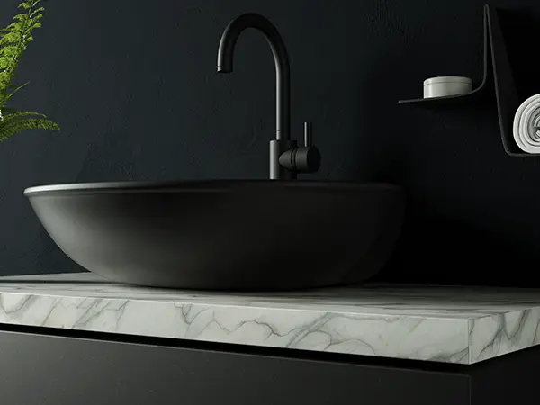 A quartz countertop in a bathroom with a dark vessel sink and black water fixture