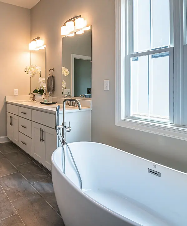 A freestanding tub with a white, double vanity and two sconces
