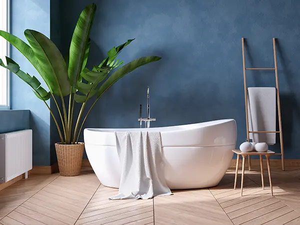 A freestanding tub in a bathroom with walls painted blue and hardwood flooring