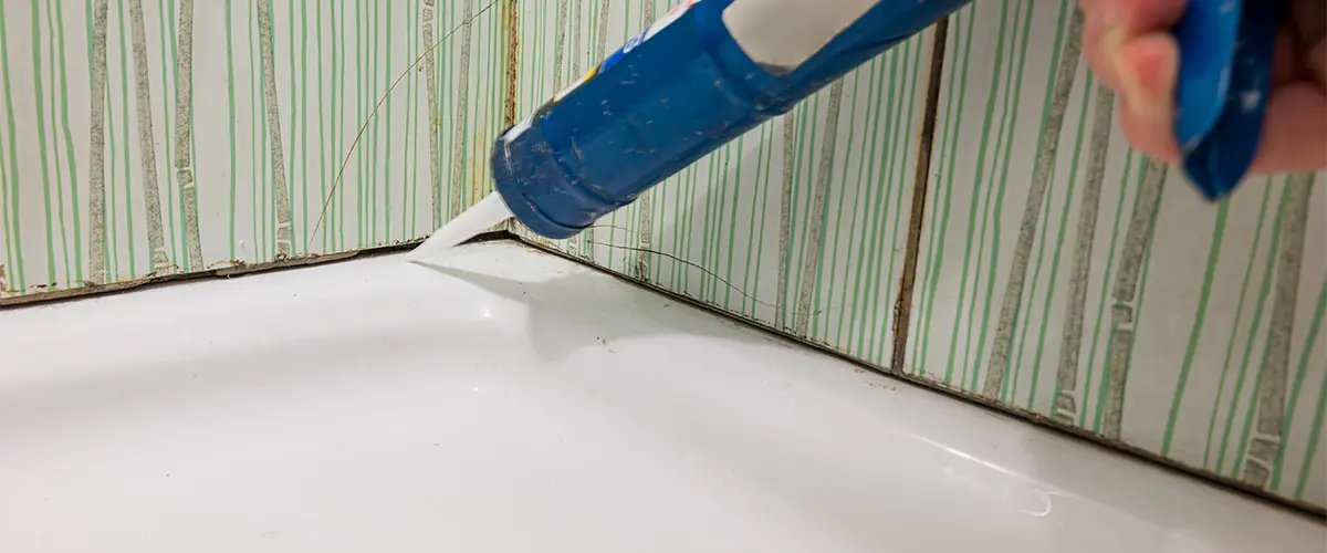 A contractor ready to apply caulk and grout in a bathroom
