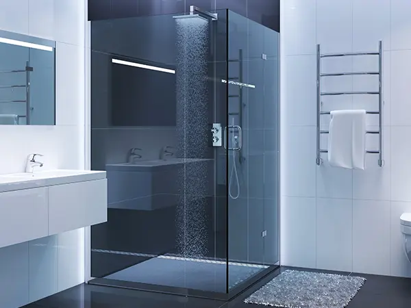 A glass walk-in shower with dark blue tiles
