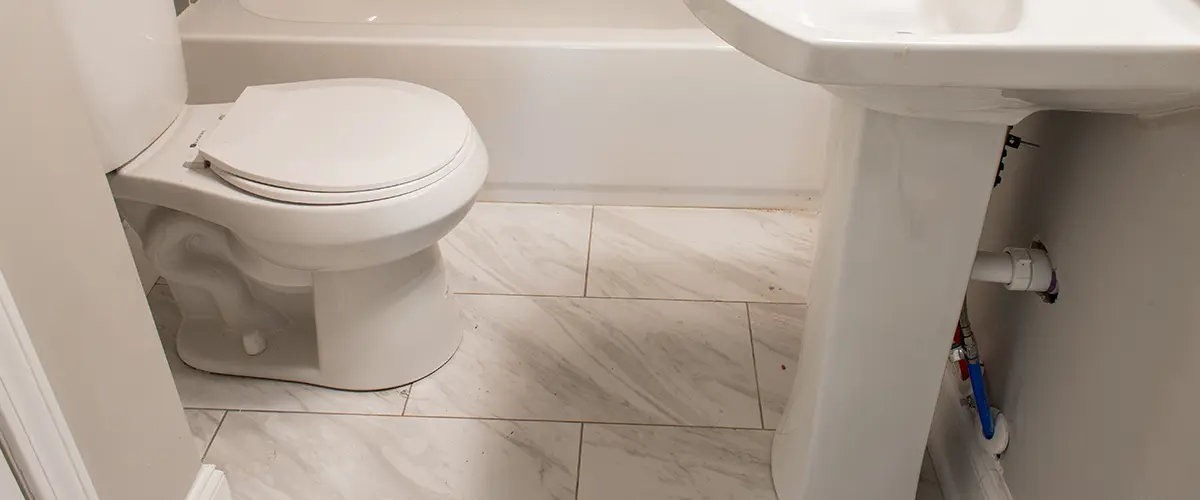 A tile flooring with a pedestal sink and a toilet