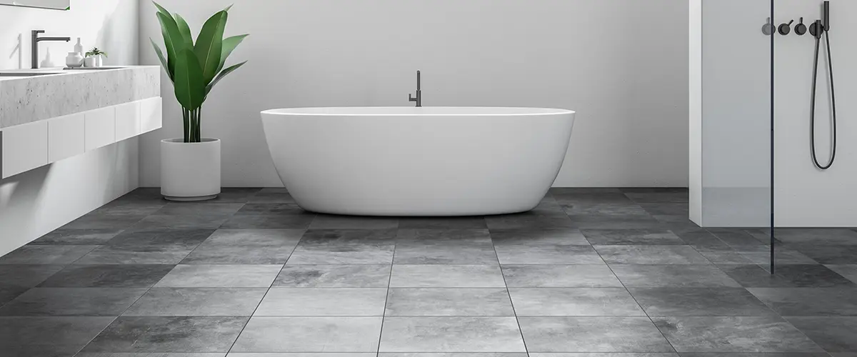 Dark gray tile flooring with artificial plant and freestanding tub