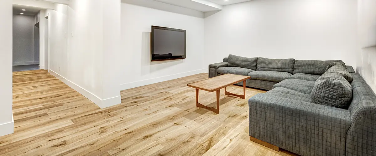 A basement remodel with a large couch and wood flooring