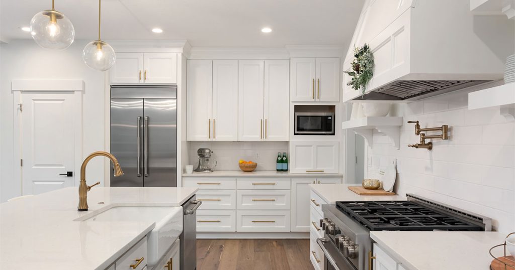Kitchen cabinet styles in a space with white cabinets and golden hardware